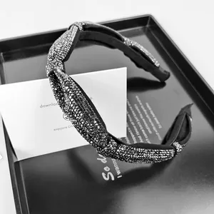 Close-up of elegant black twisted headband with dark grey rhinestones on a metal tray