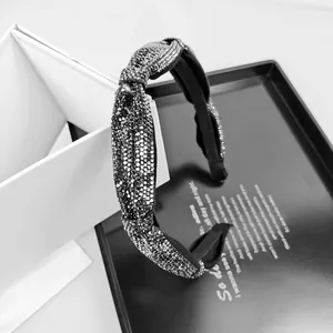 Close-up of sparkling rhinestone knotted headband on an elegant gift box setup