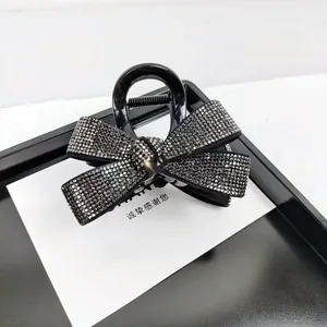 Vue détaillée de la pince à cheveux noire élégante ornée de nœuds en strass