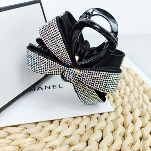 Détail de la pince à cheveux nœud noir ornée de strass brillants sur un coffret