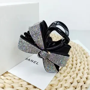 Détail d'une pince à cheveux élégante avec nœud noir et strass brillants sur une carte