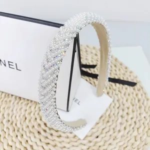 Detail of a fashion headband with white pearls and sparkling rhinestones on a beige base