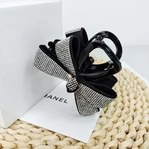 Détail d'une pince à cheveux nœud noir ornée de strass brillants sur fond de luxe