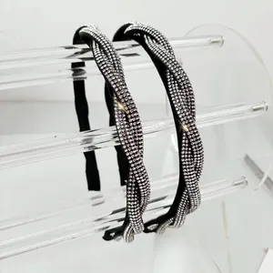 Detailed view of two twisted rhinestone headbands featuring silver crystals and black base