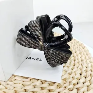 Détail d'une pince à cheveux noire à nœud avec des strass étincelants sur fond cadeau