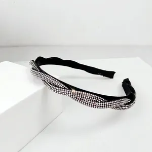 Close-up of elegant black twisted headband with pavé silver rhinestones on white blocks