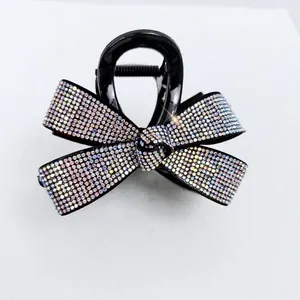 Détail de la pince à cheveux noire avec nœud et strass colorés aux reflets irisés