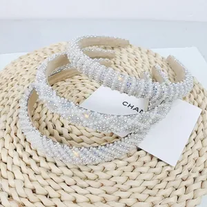 Detailed view of pearl and rhinestone headbands set on a rustic straw texture base