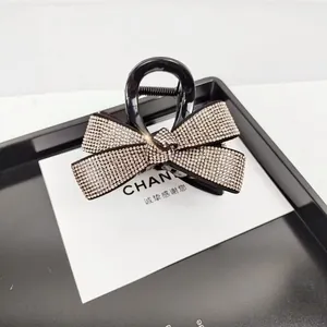 Gros plan d'une pince à cheveux nœud noir avec strass brillants et ressort métallique