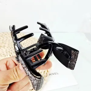 Detail of elegant black hair claw clip with bow shape and sparkling rhinestones