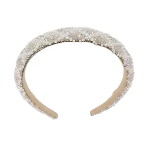 Padded headband adorned with white pearls and sparkling rhinestones on beige suede fabric