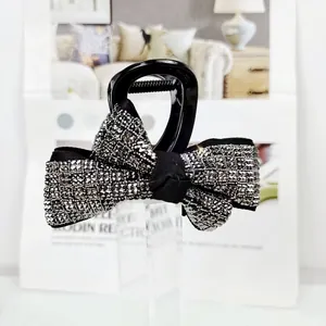 Détail d'une grande pince à cheveux avec nœud en satin noir et strass argentés brillants