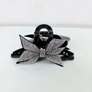 Dettaglio di elegante pinza per capelli nera con fiocco decorato da strass colorati brillanti