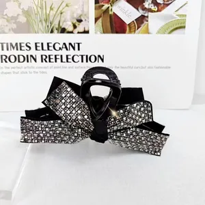 Close-up of elegant black bow hair claw clip with silver rhinestones and glossy finish