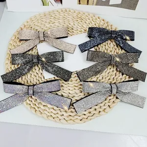 Detail view of six crystal-encrusted bow hair clips in multiple colors on a woven mat