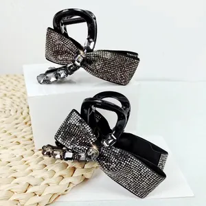 Detailed macro view of two black bow hair claws with sparkling rhinestones and crystal accents