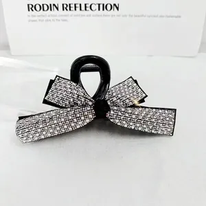 Macro shot of large black bow hair claw clip encrusted with sparkling white rhinestones