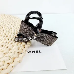 Detailed view of luxury black hair claw clip with crystal rhinestones and bow design