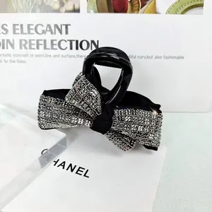 Détail d'une pince à cheveux nœud noir ornée de strass brillants sur fond blanc