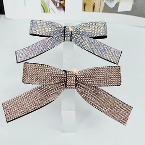 Sparkling rhinestone bow hair clips in silver and rose gold on a clear stand