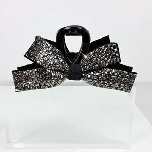 Detailed view of luxury black bow hair claw clip with sparkling square rhinestones