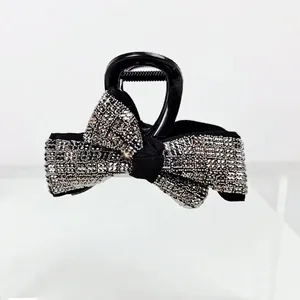 Détail macro de l'élégante pince à cheveux noire avec un nœud serti de strass