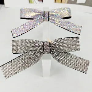 Detailed view of luxury bow hair clips with full rhinestone inlay in silver and iridescent