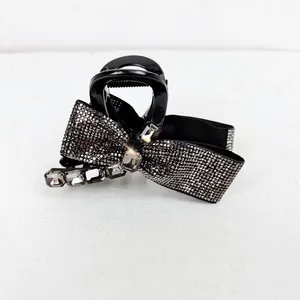 Close-up of elegant black bow hair claw clip with shimmering rhinestones and crystals