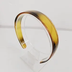 Detail view of amber gradient headband with non-slip teeth on a clear display stand