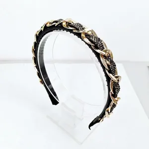Close-up of luxury baroque headband featuring gold metal chains and black crystal beads