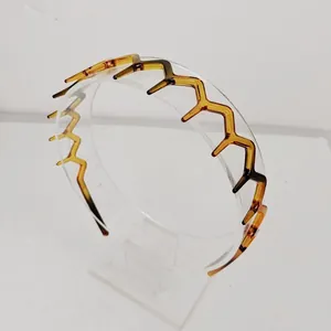 Macro view of amber wavy zigzag headband with anti-slip teeth on a clear display stand