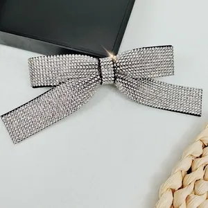 Macro detail of luxury silver rhinestone bow hair clip with central black ribbon accent