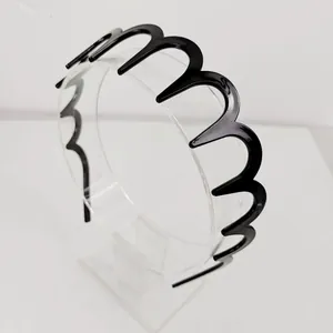 Close-up of wavy black zig-zag headband design with glossy resin finish for hair styling