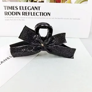 Détail d'une grande pince à cheveux nœud noir sertie de strass pour femme élégante