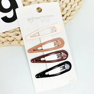 Close-up of four teardrop hair clips in earth tones on a branded white paper card