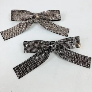 Detail of luxury double bow hair clips with shimmering grey rhinestones on black fabric