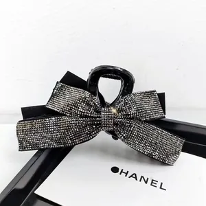 Vue détaillée d'une pince à cheveux noire avec un nœud serti de strass brillants
