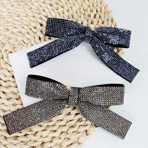 Detailed view of silver and blue rhinestone bow hair clips on a textured background