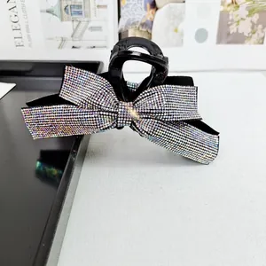 Gros plan sur une grande pince à cheveux noire ornée d'un nœud en strass multicolores