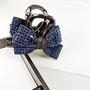Detailopname van glanzende zwarte haarklem met elegante strikaccenten van blauwe strass