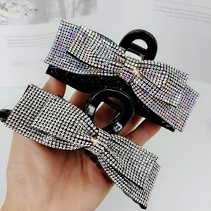 Elegant bow-shaped hair claw clips with shimmering AB and white rhinestones in hand