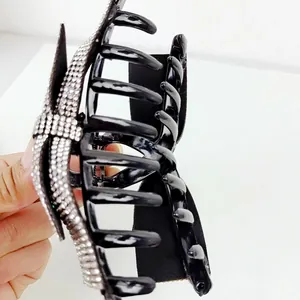 Close-up of a luxury black hair claw clip featuring a sparkling double-layer rhinestone bow