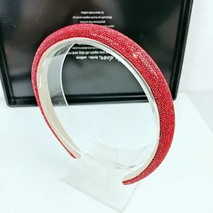 Gros plan d'un serre-tête rouge épais orné de strass sur un support de présentation