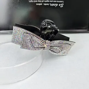 Macro detail of bow-shaped hair claw clip with colorful rhinestones on a glass stand