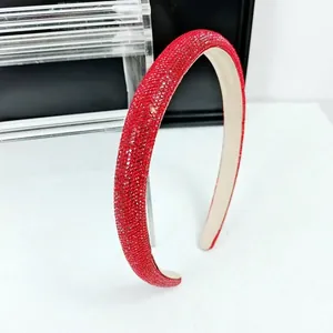 Détail du serre-tête rembourré rouge avec strass denses sur support minimaliste