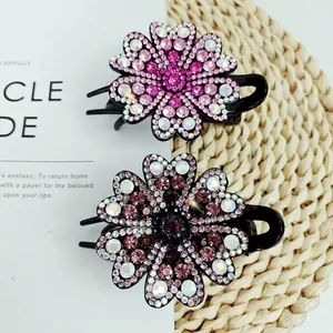 Elegant floral hair claws with gradient crystals in pink and grey, set on straw mat background