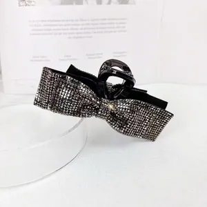 Macro detail of high-end rhinestone bow hair claw with glittering dark crystals on black