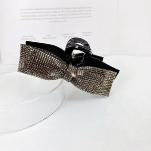 Close-up of elegant black hair claw clip with shimmering rhinestones in a bow shape