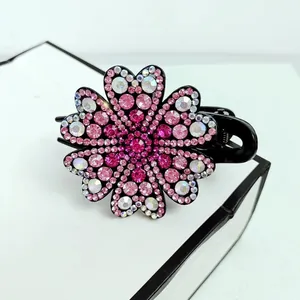 Macro shot of elegant floral hair claw clip featuring pink rhinestones and black base