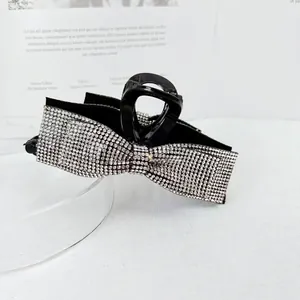 Macro detail of luxury bow hair claw clip featuring shimmering silver rhinestones
